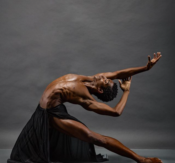 Luís Fernando, ex-aluno da companhia Vidançar, executa um passo de balé durante um ensaio fotográfico. O dançarino está sem camisa e utiliza apenas uma saia preta.